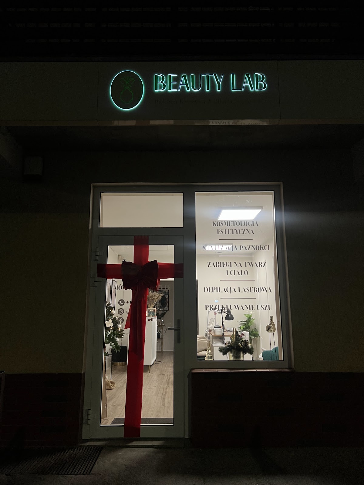 Witryna Beauty Lab w Elblągu wieczorem, udekorowana kokardą